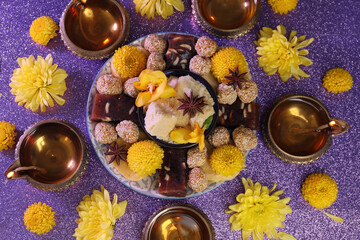Obraz na płótnie Canvas Diwali celebration. Flat lay composition with diya lamps and tasty Indian sweets on shiny violet table