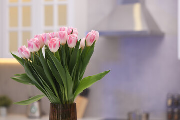 Beautiful bouquet of fresh pink tulips in kitchen. Space for text