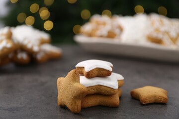 Decorated cookies on grey table against blurred Christmas lights, closeup