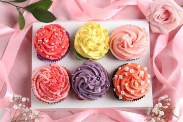 Delicious cupcake with bright cream on pink fabric, top view