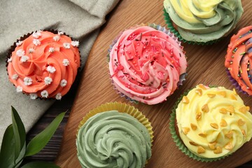 Delicious cupcake with bright cream on wooden table, flat lay