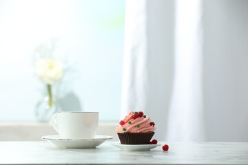 Delicious cupcake with pink cream and tea on white table