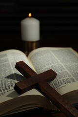 Wooden cross, Bible and church candle on table