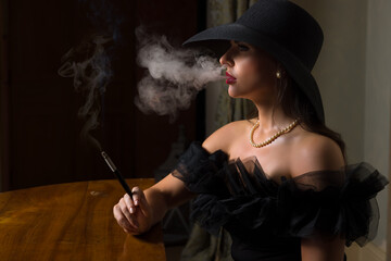 Lady in black hat blowing smoke