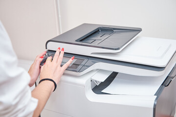 Fototapeta premium unrecognizable Business woman using a printer. Business woman printing a document for a new company project.