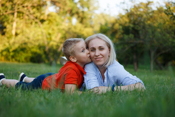 The mother and child lie together on the grass, spend time together in the park.