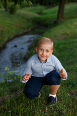 Cute little boy sitting on the grass, looking at camera.