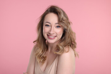 Fototapeta premium Portrait of smiling woman on pink background