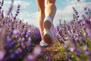  Back view of woman's legs with sport shoes jogging in through vield of lavender flowers © Firn