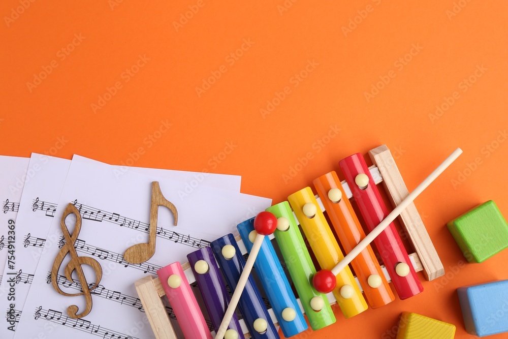 Poster Tools for creating baby songs. Flat lay composition with xylophone on orange background. Space for text