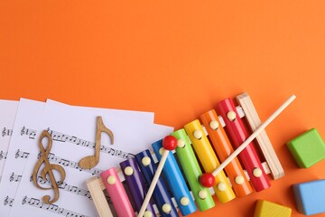 Tools for creating baby songs. Flat lay composition with xylophone on orange background. Space for text - obrazy, fototapety, plakaty