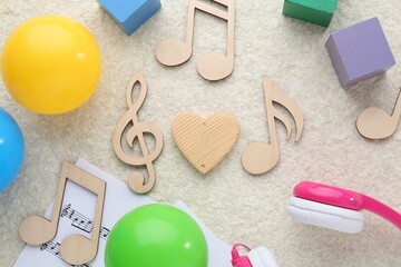 Wooden notes, music sheets and toys on beige textured background, flat lay. Baby song concept