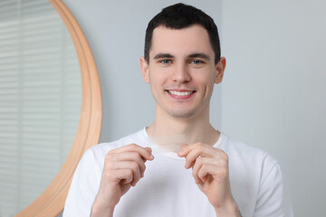 Young smiling man with whitening strips indoors