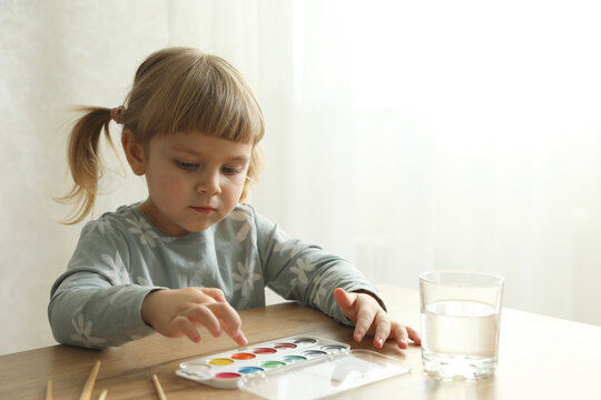 Cute little girl with supplies for drawing at wooden table indoors. Child`s art