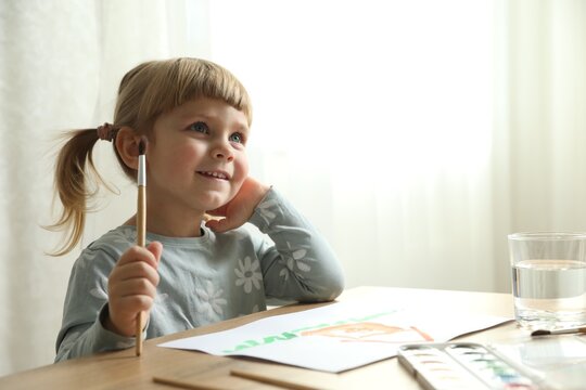 Cute little girl drawing at wooden table indoors. Child`s art