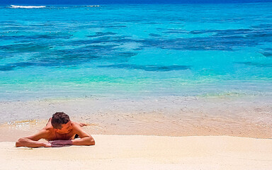 Fototapeta na wymiar Man lying on beach sand and water on tropical beach Maldives.