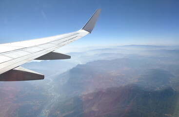 plane wing and mountain of China on sky through window frame