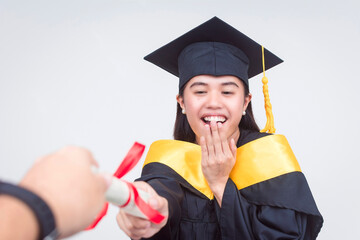 Excited young woman in graduation cap and gown receives her college diploma, expressing joy....