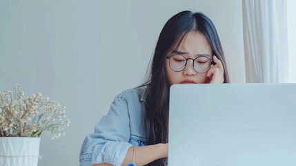 Young Asian woman are stressed and tired from work. She was holding glasses at a white desk with a laptop in the office.