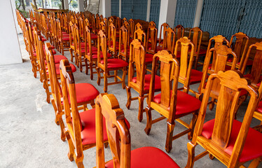 View of wooden chairs and red cushions arranged in rows on the concrete floor.
