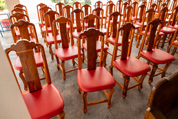 View of wooden chairs and red cushions arranged in rows on the concrete floor.