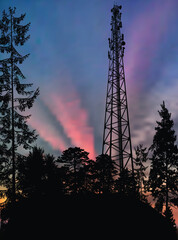 antenna tower silhouette in black forest at pink sky background