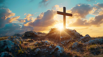 A wooden cross is placed on top of a rocky hill. The sky is blue with white clouds and a bright sun is shining 