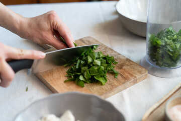 Female slicing spinach on a chopping board. Healthy cooking at home