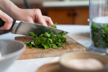 Woman slicing spinach on a chopping board. Healthy cooking at home