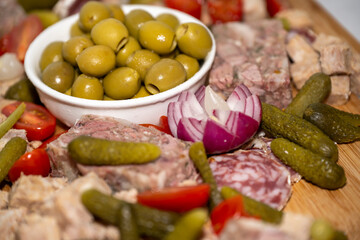 vol d'olives vertes sur un plateau de charcuterie avec un oignon rouge, des tomates et des cornichons