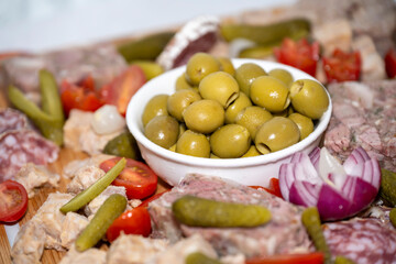 vol d'olives vertes sur un plateau de charcuterie avec un oignon rouge, des tomates et des...