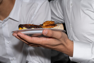 main d'un jeune homme tenant une assiette avec des gâteaux salés lors d'un brunch