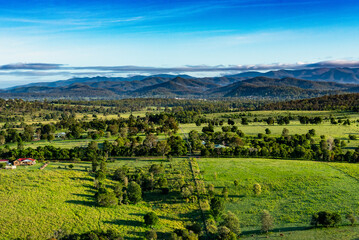 Fototapeta na wymiar Vue aérienne d'un paysage de la campagne située à l'Ouest de la ville d'Ipswich (Queensland, Australie). En arrière plan une chaine de montagnes coiffée de quelques nuages.