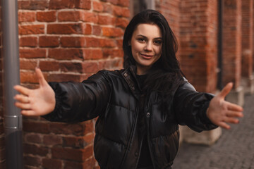 Beautiful brunette young woman wear black puffer jacket looking at the camera smiling with open...