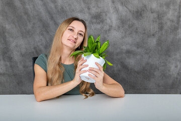 Blonde-haired Girl Sitting at Table Fixated on Green Flower in Pot