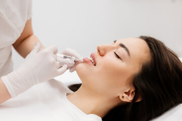 Obraz na płótnie Canvas The doctor cosmetologist makes Lip augmentation procedure of a beautiful woman in a beauty salon.Cosmetology skin care. High quality photo