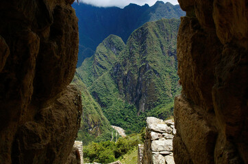 Panoramic view of the Peruvian Andes from a glimpse of a stone house in the famous Inca archaeological site of Machu Picchu designated a UNESCO World Heritage Site in 1983