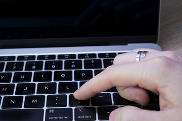 Young Caucasian woman's hand pressing the button . on the keyboard of a laptop computer.