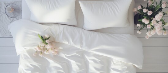 A top-down view of an elegant bed covered in soft white duvet bedding and pillows. The pristine white sheets create a clean and inviting atmosphere.