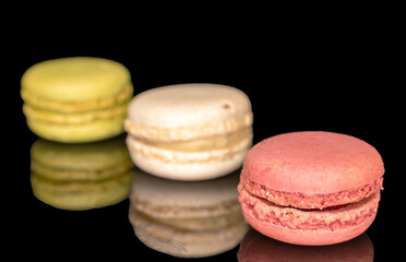 Three sweet macarons, macro, isolated on black background.