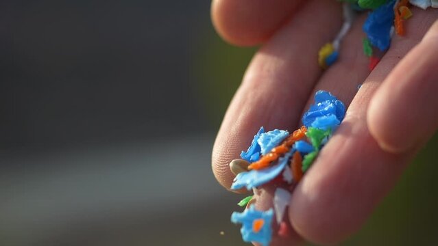 pieces of microplastic falling slow motion. colorful plastic fragments close up, plastic waste, plastic pollution, environment. microplastics in hands