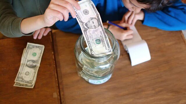 Children counting money, inserting dollar bills into labeled savings jar, representing financial literacy and responsible money management skills
