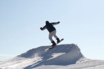Naklejka na ściany i meble A snowboarder rides a snowboard. Winter recreation.Snowboarding on the mountain.