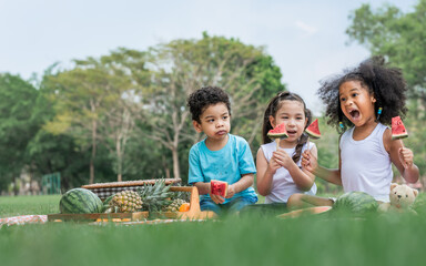 Three mixed race caucasian little cute children kids sitting, playing in outdoor green park for...