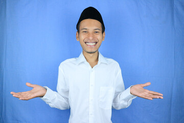 Smiling of excited muslim asian man wearing cap with open hand gesture