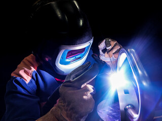person in helmet welding with TIG