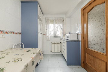 kitchen with blue and white furniture, light blue stoneware floors and wooden and glass access...