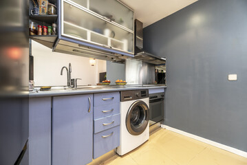 Loft apartment with open kitchen with blue furniture, stoneware floors, gray walls and gray...
