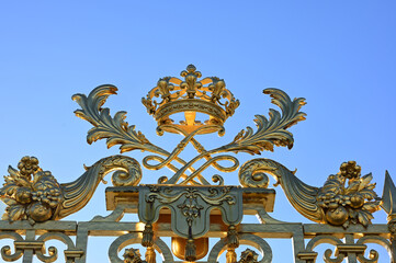 Fototapeta na wymiar Versailles, Paris, France, June 30, 2022. Gorgeous detail of the golden gate of the royal palace. The late afternoon light enhances its brilliance.