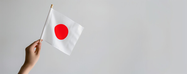 A hand holding a white flag with the flag of japan